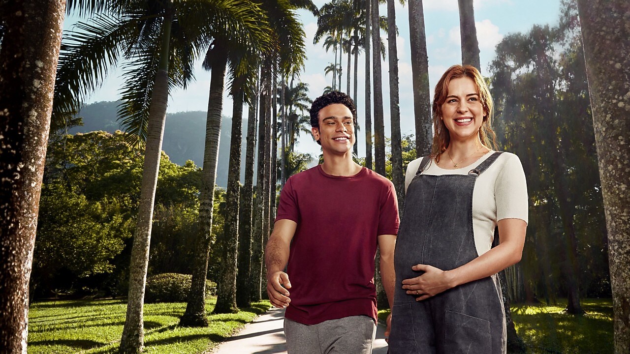Mulher negra segurando caneca em frente ao seu computador em sala toda decorada com plantas
