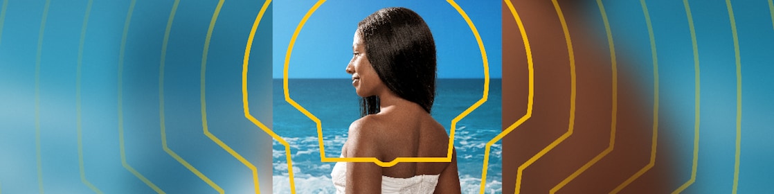 Uma mulher de pele negra olhando para o mar.