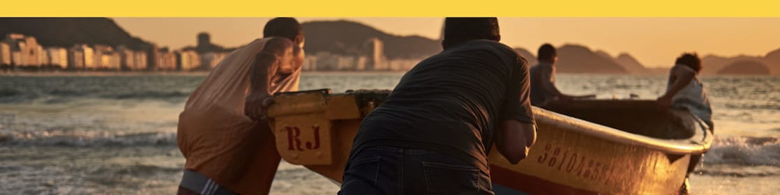 No centro da imagem temos um grupo de pescadores empurrando um barco em direção ao mar