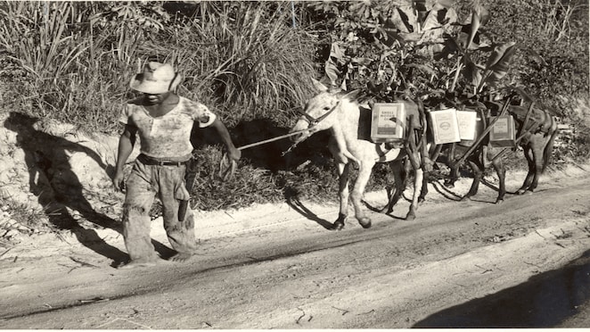 Na imagem, homem carrega os primeiros barris de gasolina da Shell.