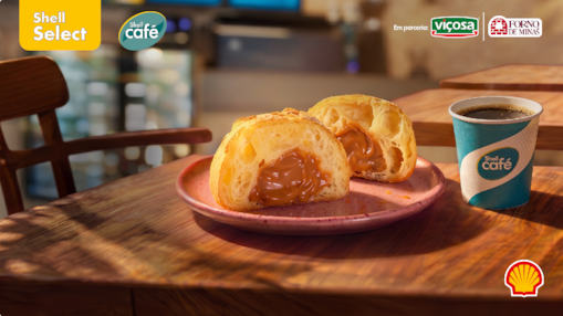 Imagem de pão de queijo com doce de leite sobre uma mesa, com café da Shell Café ao lado, logos de Shell Select e Shell Café e dos parceiros Viçosa e Forno de Minas e concha da Shell