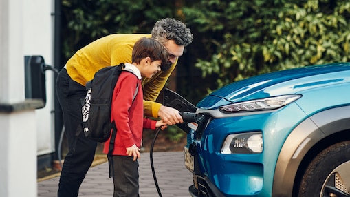Pai e filho realizando recarga de carro elétrico em um posto Shell
