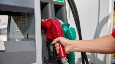 Mão de um frentista segurando bico da bomba de abastecimento