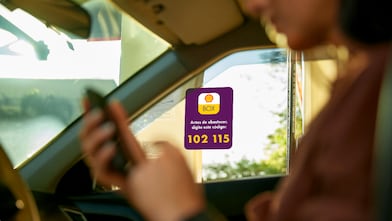 Mulher dentro de carro usando o celular para acessar o aplicativo de pagamento Shell Box