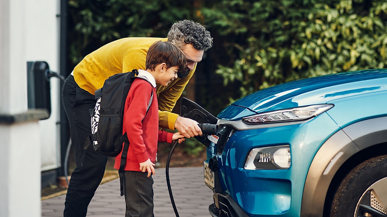 Pai e filho realizando recarga de carro elétrico em um posto Shell