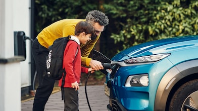 Pai e filho realizando recarga de carro elétrico em um posto Shell