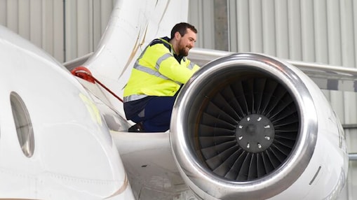 Foto mostra um homem sobre a asa de um avião realizando uma vistoria da aeronave