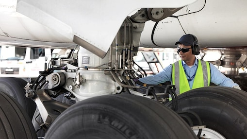 Funcionário visto embaixo de um avião trocando o seu combustível