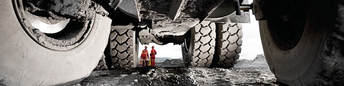 Pneus de veículos pesados com homens em uniforme de trabalho ao fundo