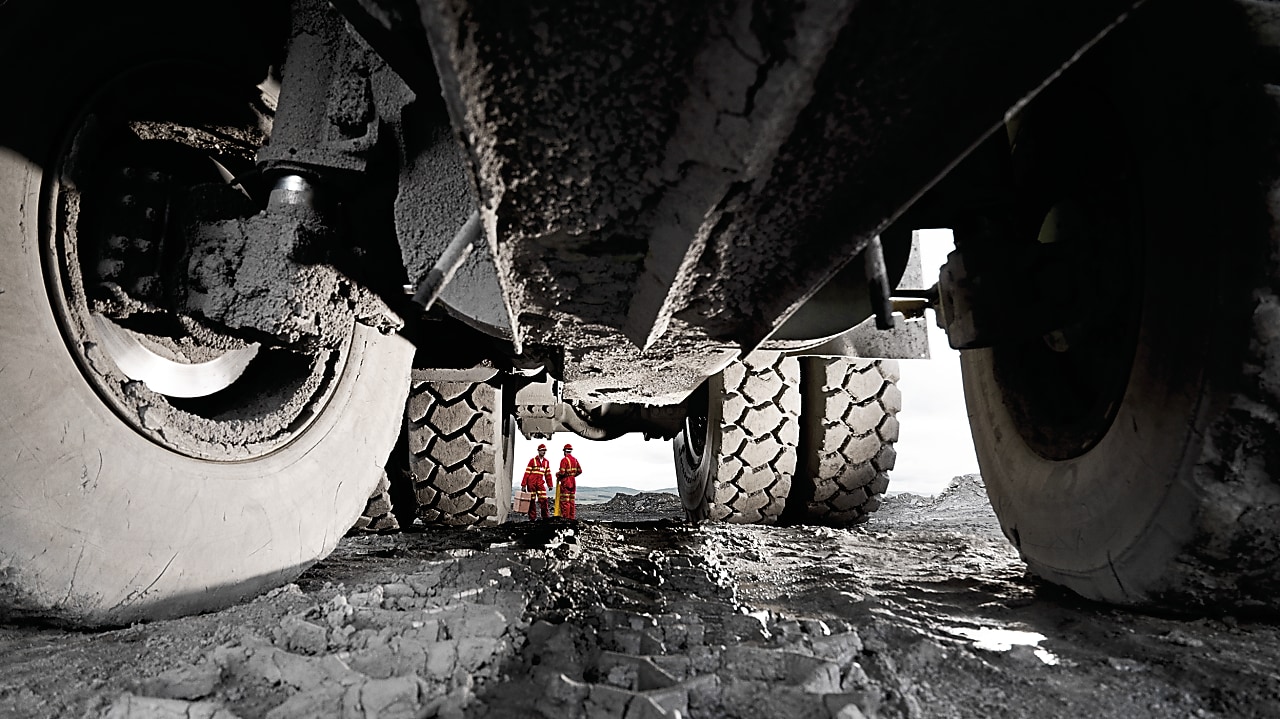 Pneus de veículos pesados com homens em uniforme de trabalho ao fundo
