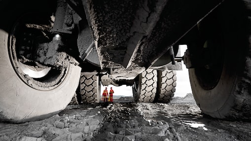 Pneus de veículos pesados com homens em uniforme de trabalho ao fundo