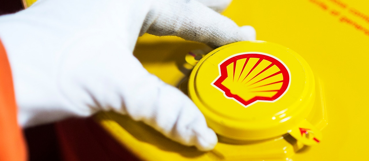 Imagem mostra mão de uma pessoa com luva abrindo recipiente com lubrificante Shell