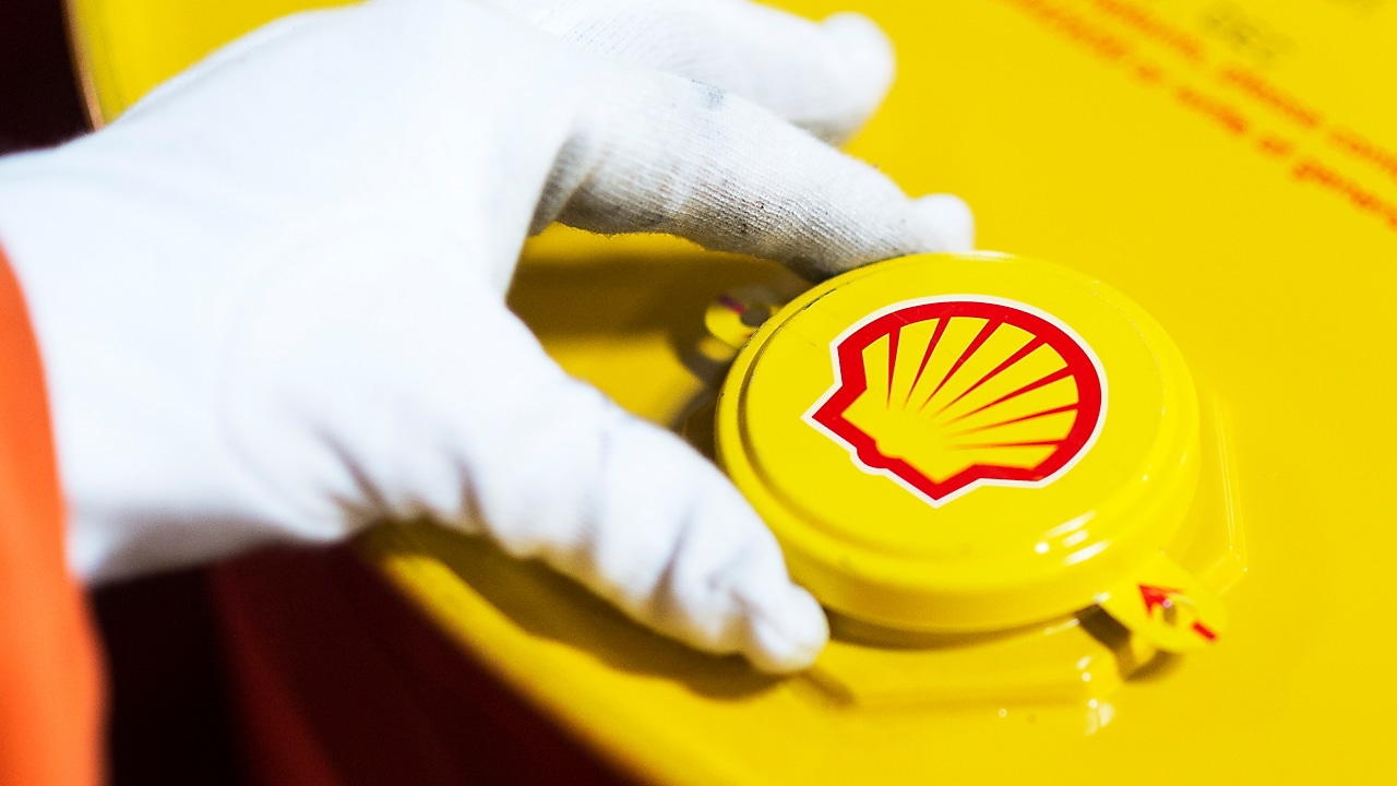 Imagem mostra mão de uma pessoa com luva abrindo recipiente com lubrificante Shell