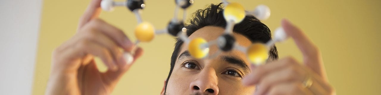 Homem jovem examinando modelo molecular