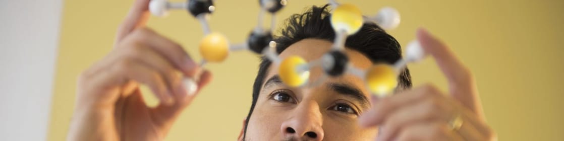 Homem jovem examinando modelo molecular