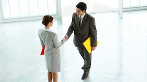Businessman and businesswoman shaking hands in lobby