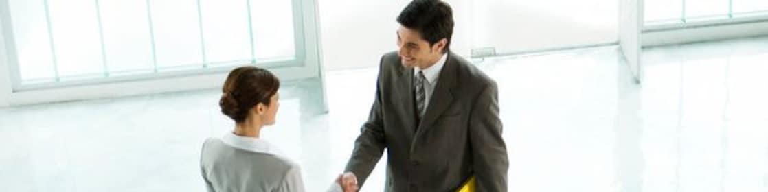 Homem e mulher de negócios apertando as mãos em um lobby