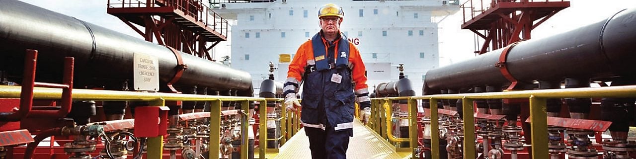 trabalhador caminhando perto de uma embarcação da Shell