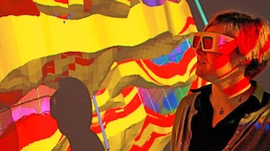 Mulher com óculos especiais examina projeção 3D em parede de mapa geológico