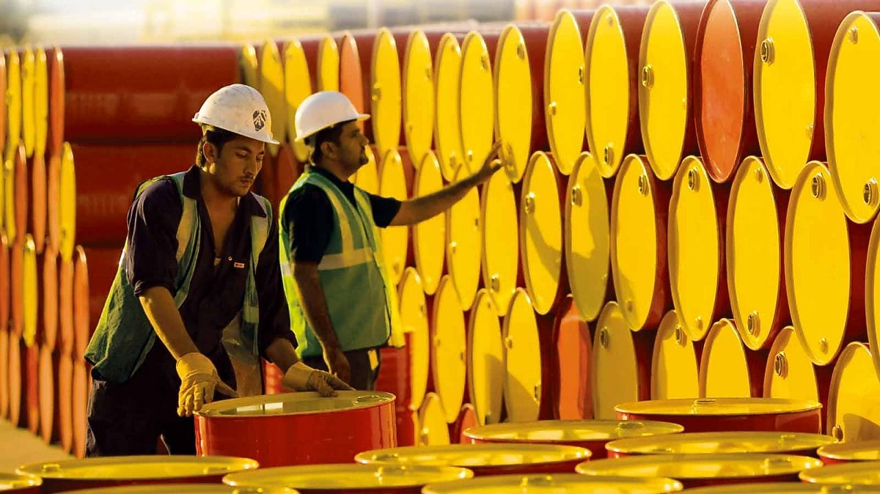 dois funcionários transportando barris da Shell