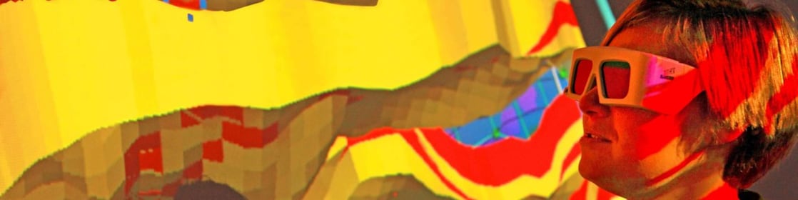 Mulher com óculos especiais examina projeção 3D em parede de mapa geológico