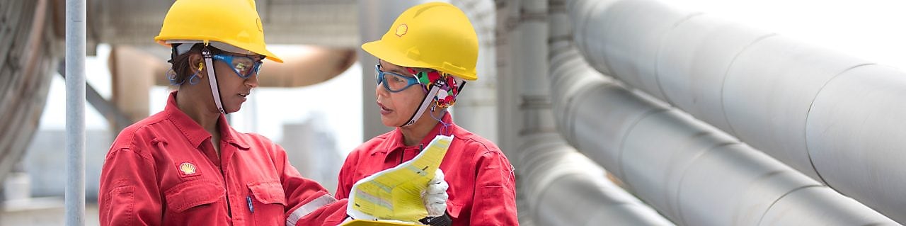 dois trabalhadores discutindo um projeto em refinaria na Malásia