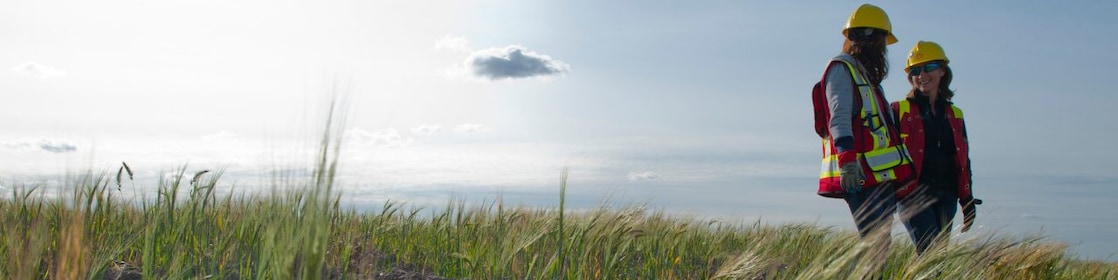 Duas engenheiras de Shell sorrindo num campo de capim verde