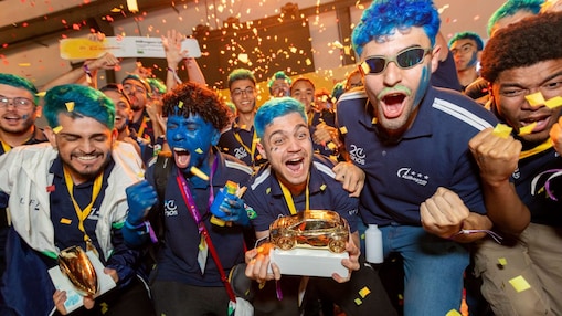 Estudantes comemoram com entusiasmo a vitória na Shell Eco-marathon, segurando troféus dourados em meio a chuva de papel picado, com rostos pintados e expressões de euforia. 