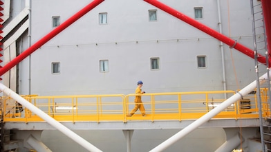 Funcionário da Shell caminha em uma plataforma de petróleo offshore.