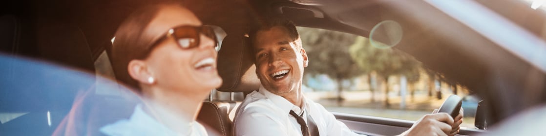 Homem dirigindo carro e mulher no corona sorrindo