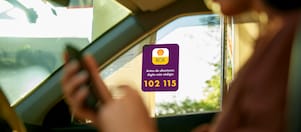 Mulher dentro de um carro usando o celular para acessar o aplicativo de pagamento Shell Box