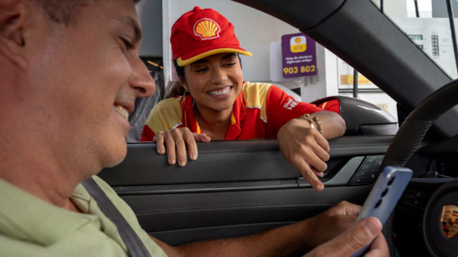 Motorista dentro de carro mexendo no celular e frentista olhando pela janela