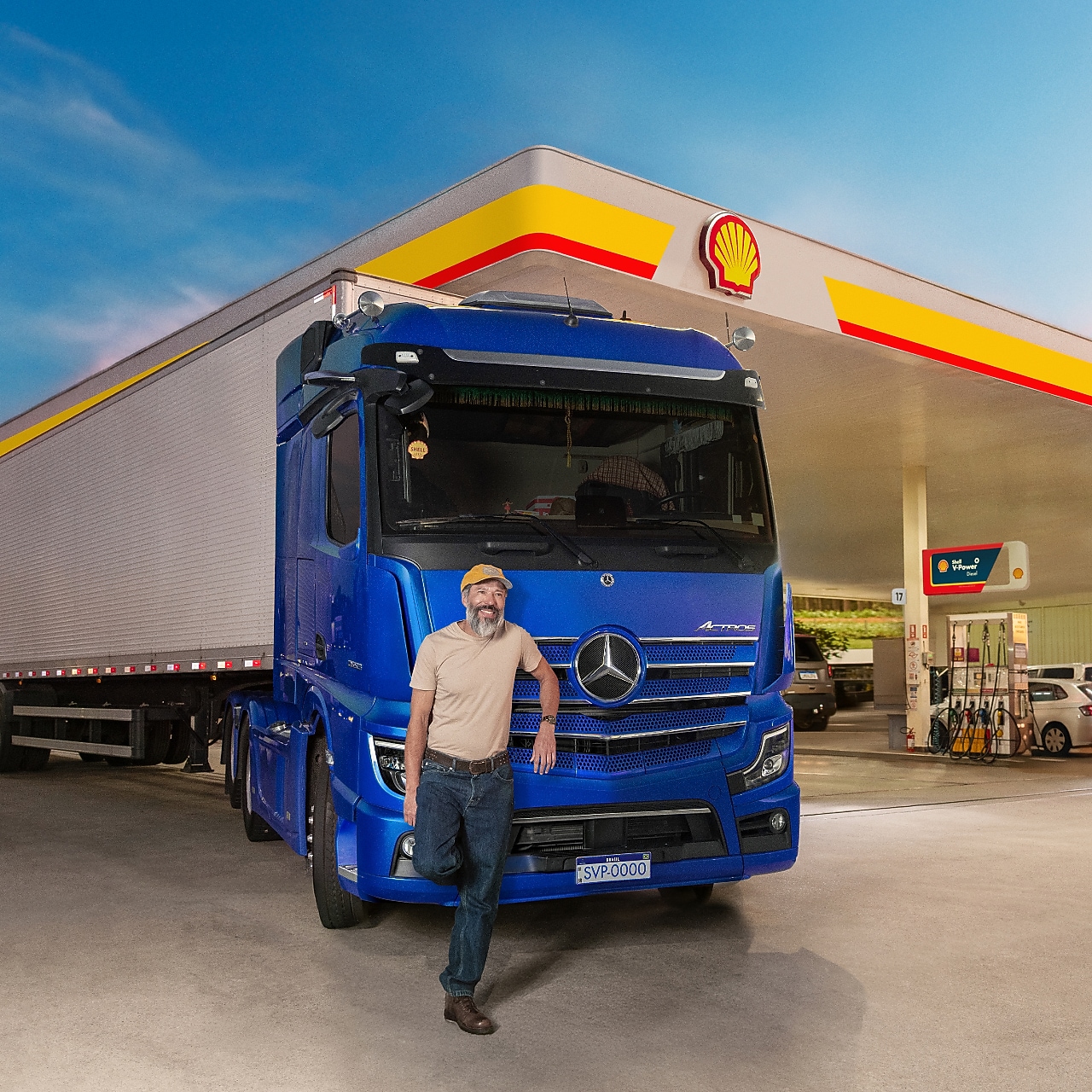 Caminhoneiro em frente a um caminhão estacionado em um posto Shell