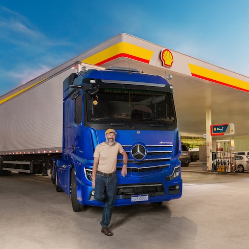 Caminhoneiro em frente a um caminhão estacionado em um posto Shell