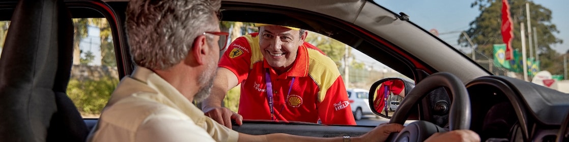 Frentista conversando com motorista, que está dentro do carro