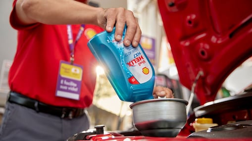 Frentista de posto Shell realizando troca de lubrificante Helix em um carro