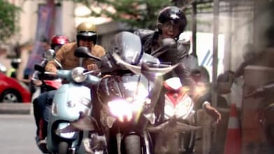 Motociclistas dirigem felizes entre carros num centro urbano