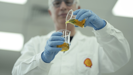 Homem com jaleco com logo da Shell realizando pesquisa em laboratório