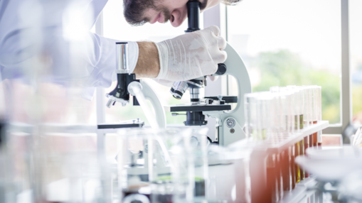 Pesquisador trabalhando em um laboratório e utilizando um microscópio