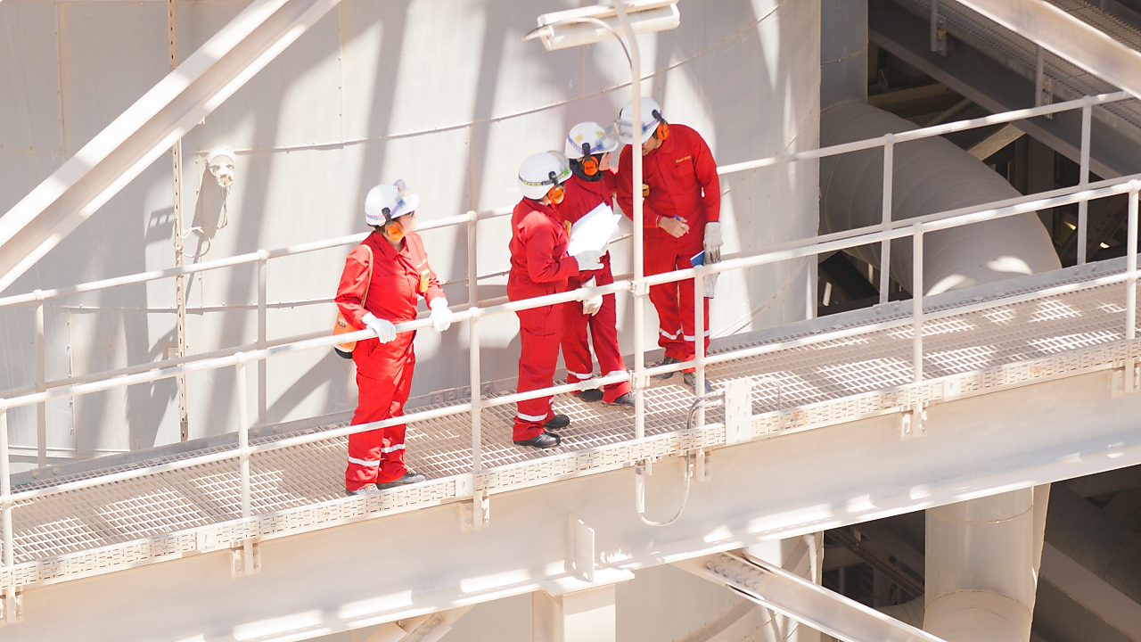 Tanque de gás natural liquefeito e, à frente, profissionais da Shell usando EPIs