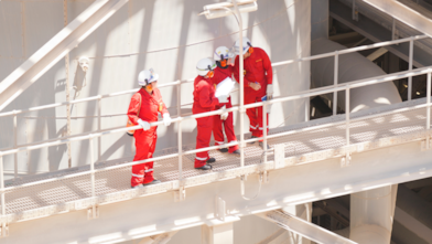 Tanque de gás natural liquefeito e, à frente, profissionais da Shell usando EPIs