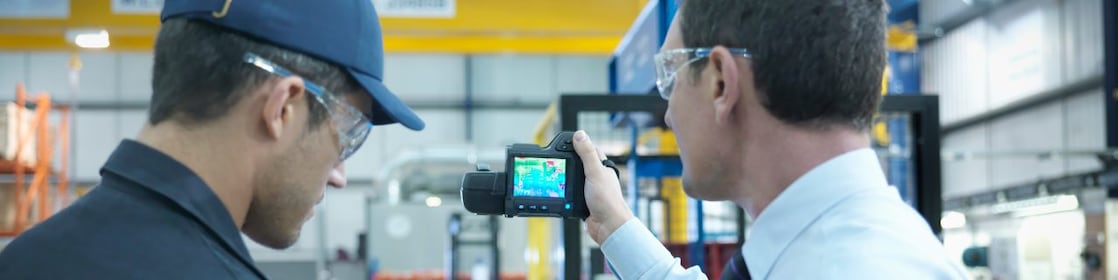 Colaboradores usando tablet digital e câmera infravermelha para verificar o uso de energia na fábrica