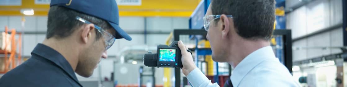 Colaboradores usando tablet digital e câmera infravermelha para verificar o uso de energia na fábrica