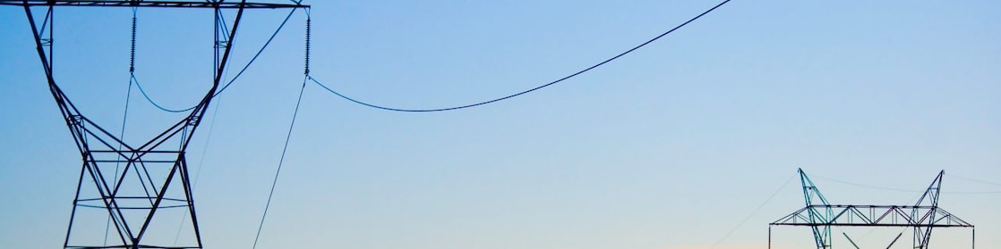 Paisagem ao pôr do sol com rede de distribuição de energia em destaque