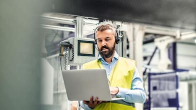 Profissional trabalha ao computador em um ambiente industrial