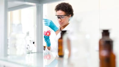 Um grupo de participantes sorrindo e posando juntos em frente a um painel amarelo do Shell Iniciativa Jovem durante um evento. Eles usam crachás de identificação e parecem fazer parte de um encontro profissional ou de empreendedorismo.