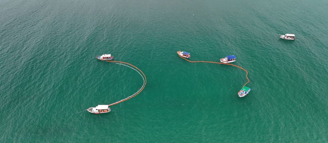 Seis barcos simulando a técnica de limpeza utilizada em situações de incidentes com vazamento de óleo no mar.