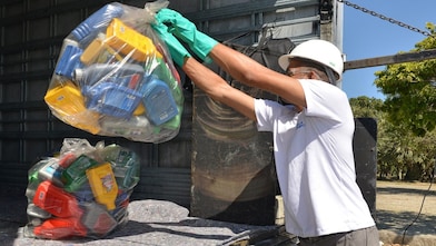 Homem segurando embalagens vazias no caminhão