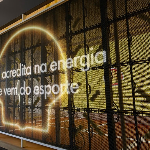 Instalação temática da Shell com iluminação em formato de cérebro e a frase ‘A Shell acredita na energia que vem do esporte’ projetada na estrutura.