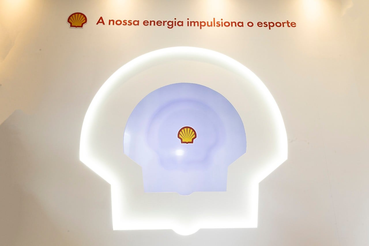 Painel iluminado com o logotipo da Shell ao centro e a frase ‘A nossa energia impulsiona o esporte’ exibida na parte superior.